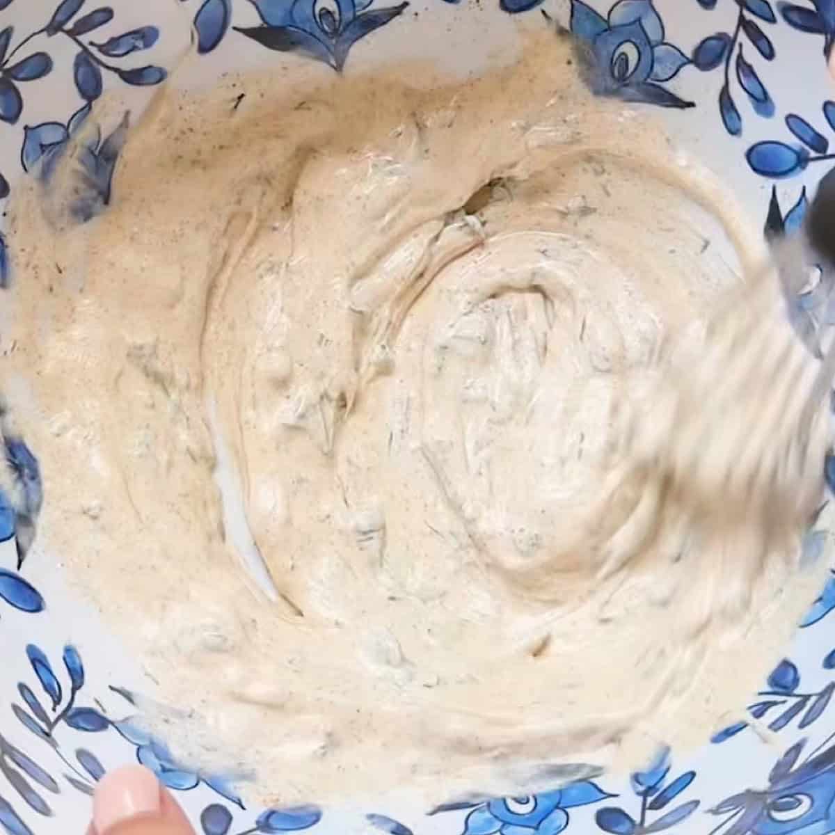 Shrimp pasta salad dressing being whisked in a mixing bowl.