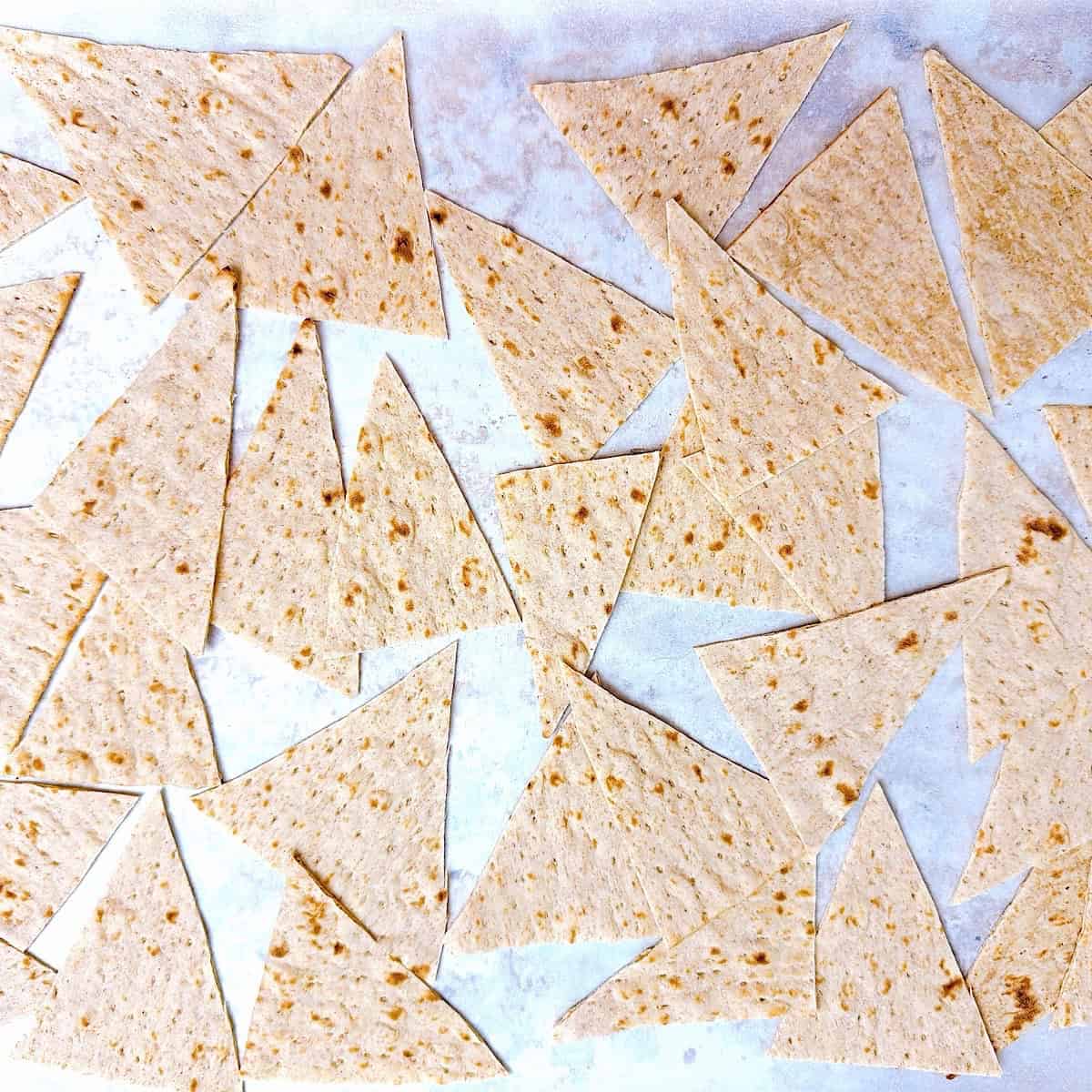 Lavash bread cut into triangles on a baking sheet with parchment paper.