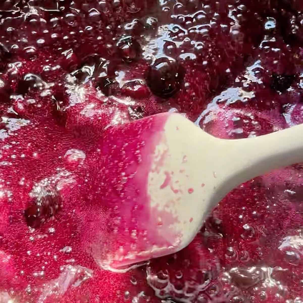 Lightly pressing the blueberries while they simmer.