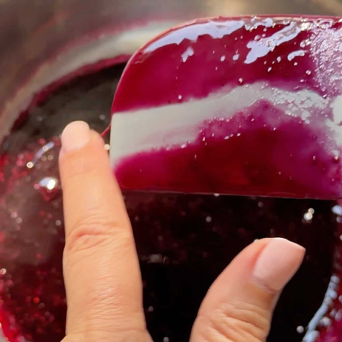 Swiping finger across the spatula with syrup to show thickness.