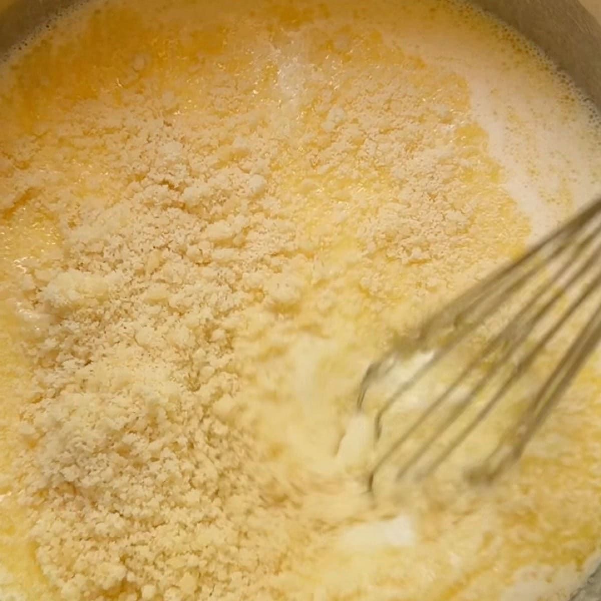 Whisking in the grated Parmesan cheese.