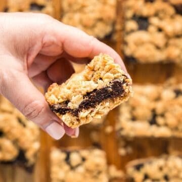 Holding a homemade fig oatmeal bar over remaining bars to show the fig filling.