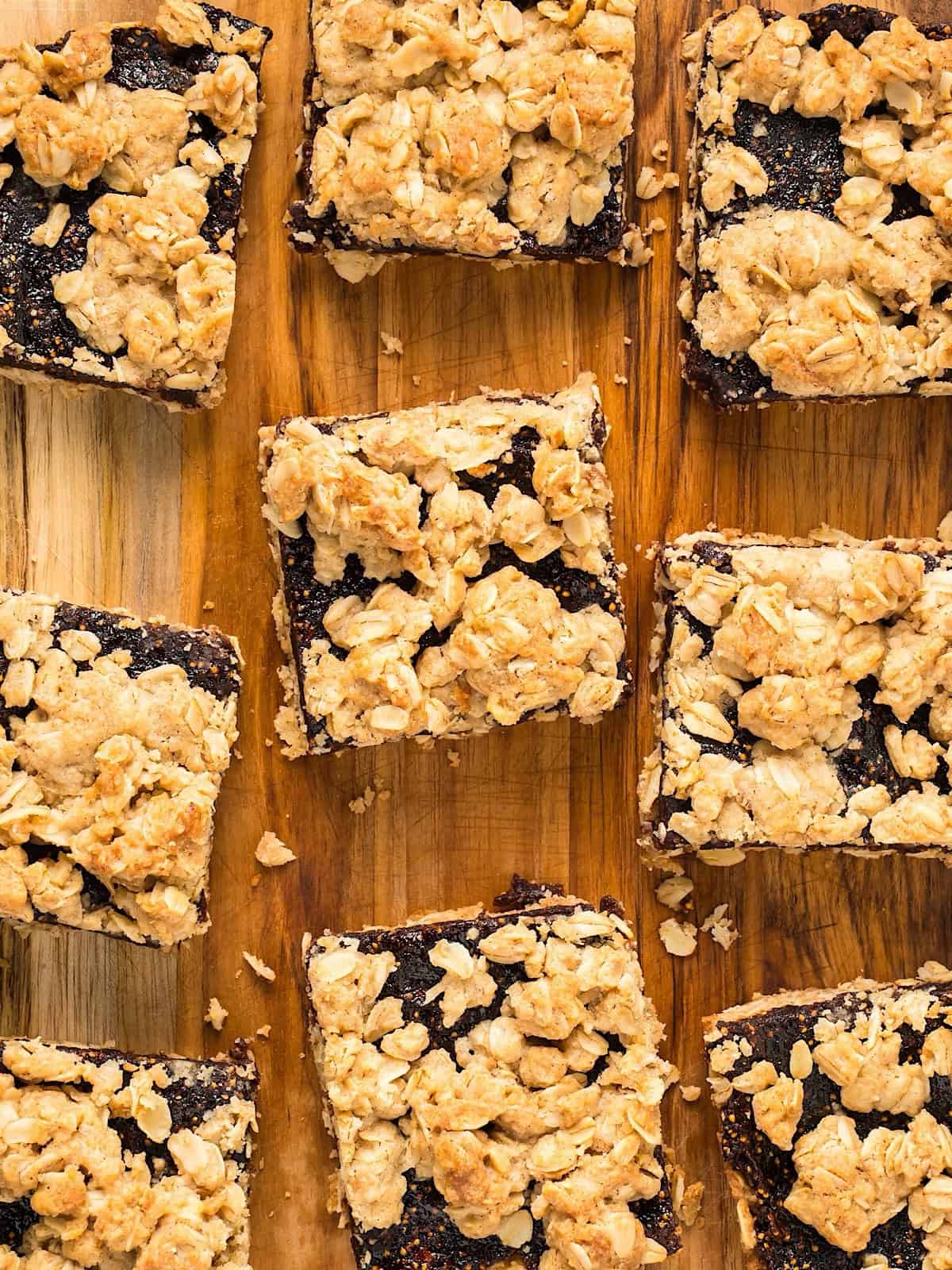Sectioned fig oatmeal bars on a decorative board with crumbs scattered.