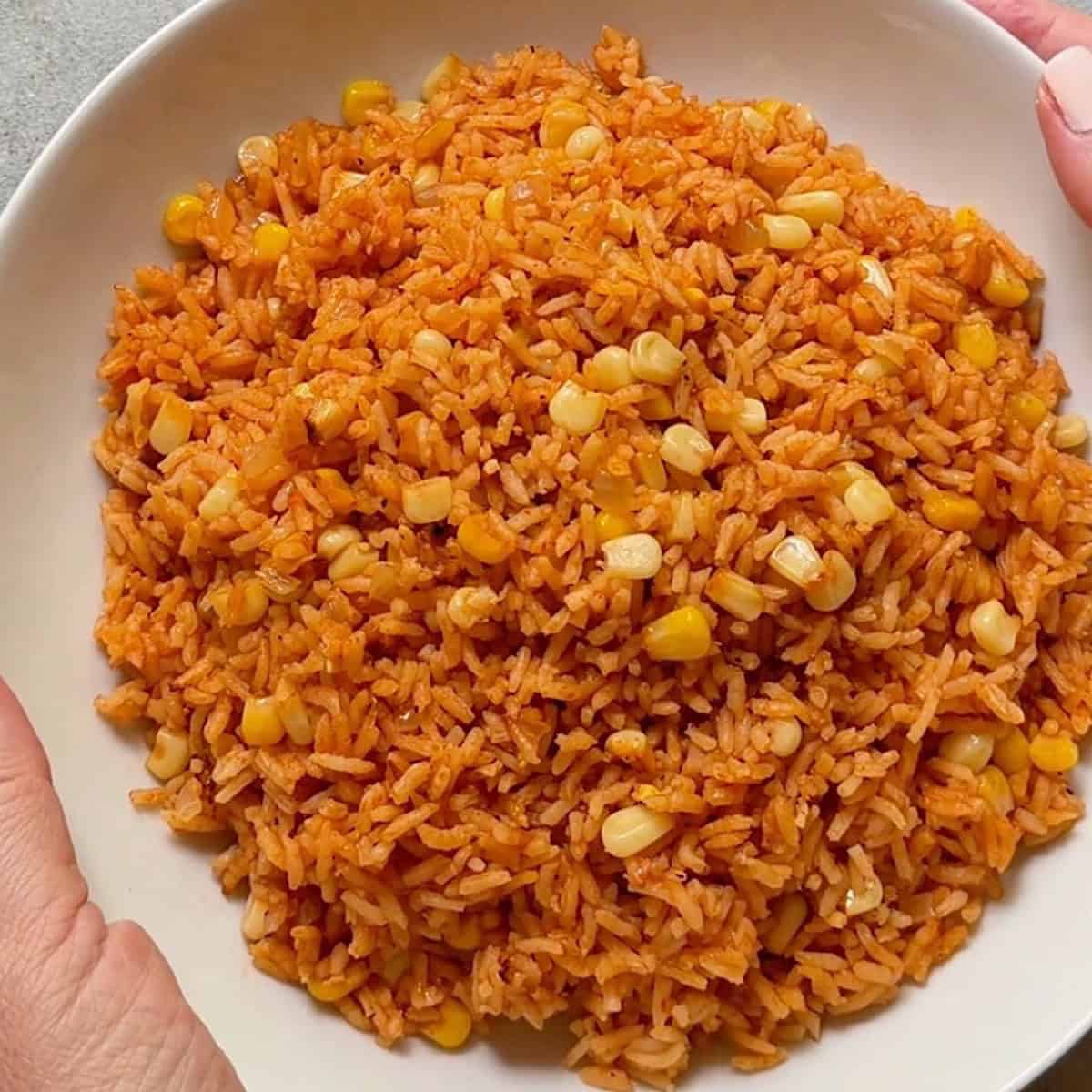 Holding a serving bowl of the Mexican corn rice.