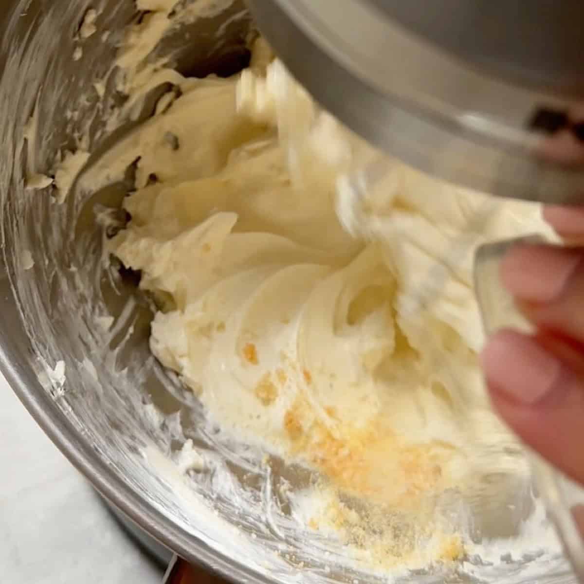 Adding garlic powder and other seasonings to the stand mixer with whipped cream cheese.