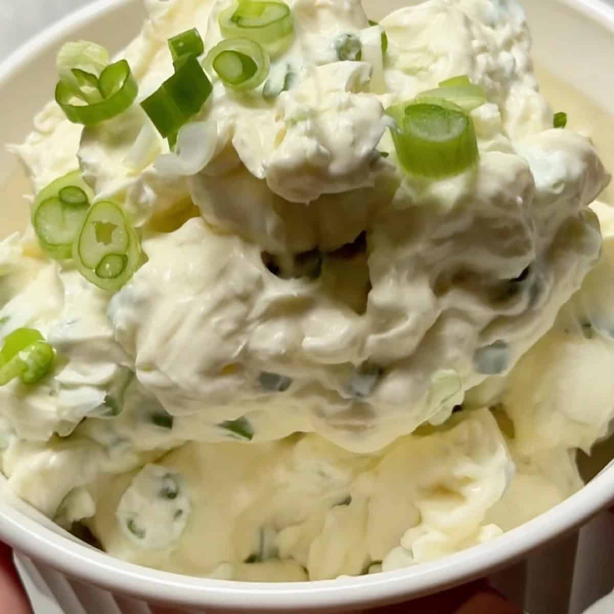 Scallion cream cheese in a bowl with scallions folded in.