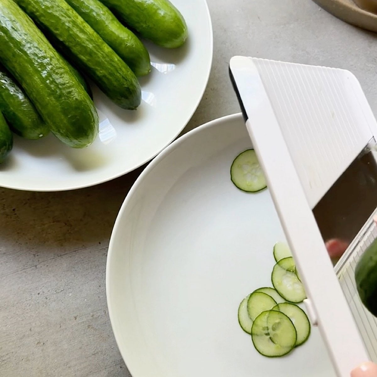 Thinly slicing Persian cucumber on a mandolin.