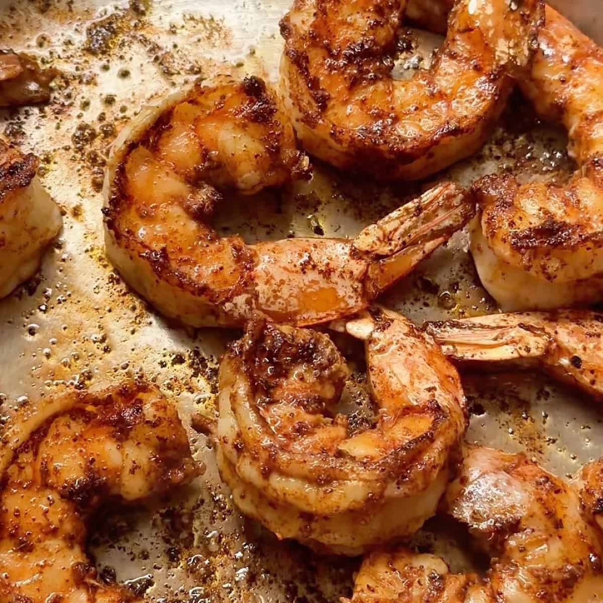 Blackened shrimp cooking in a skillet with olive oil
