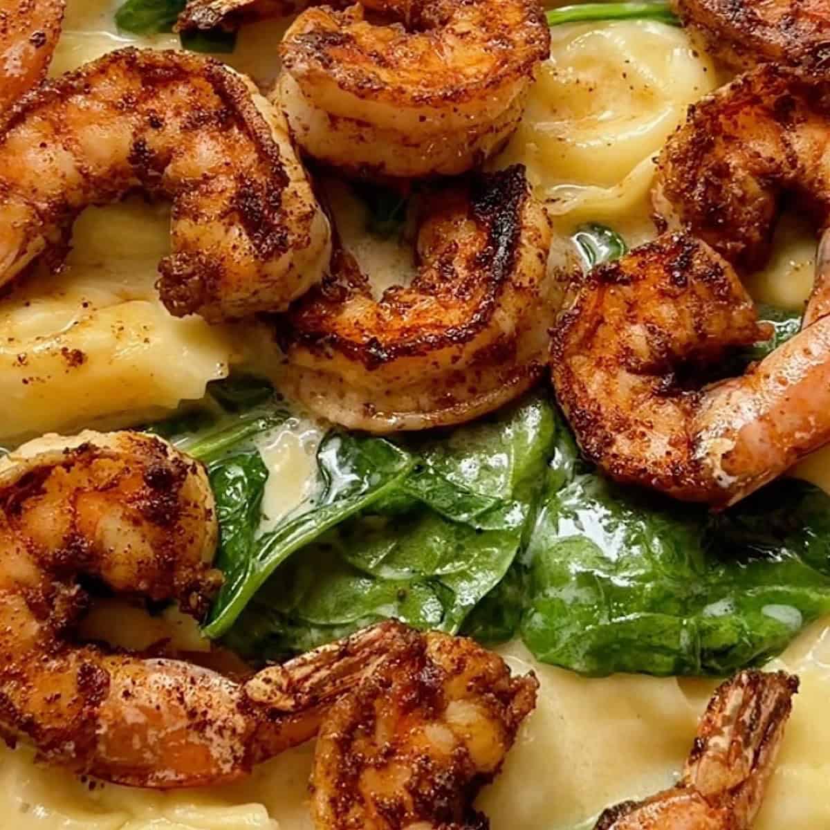 Blackened shrimp added to the tortellini alfredo skillet with wilted spinach.