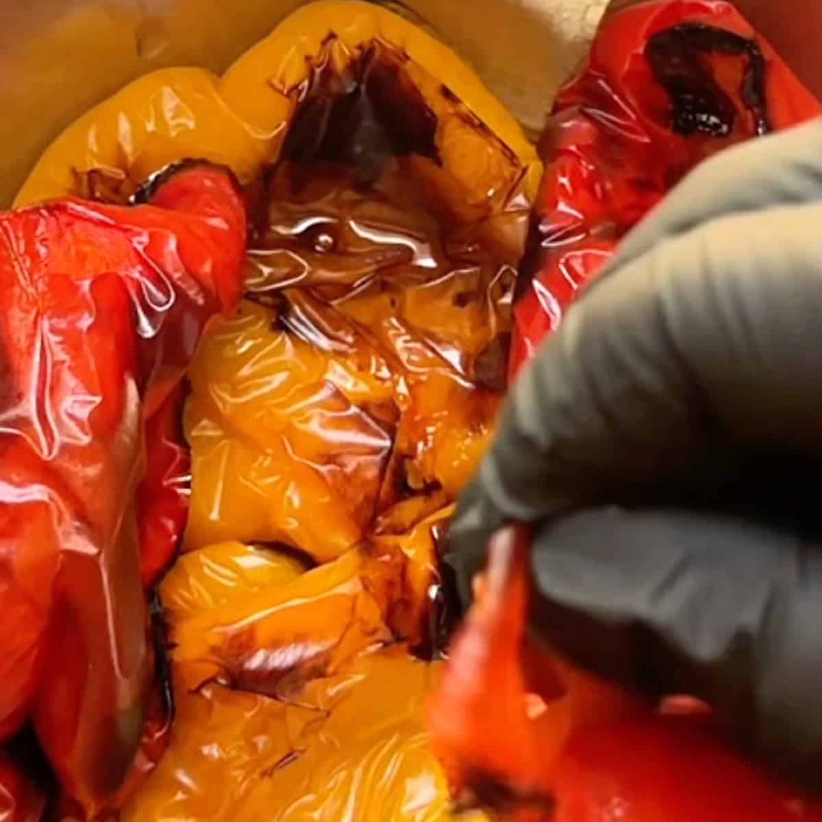 Peeling the charred skin of a blistered red pepper.
