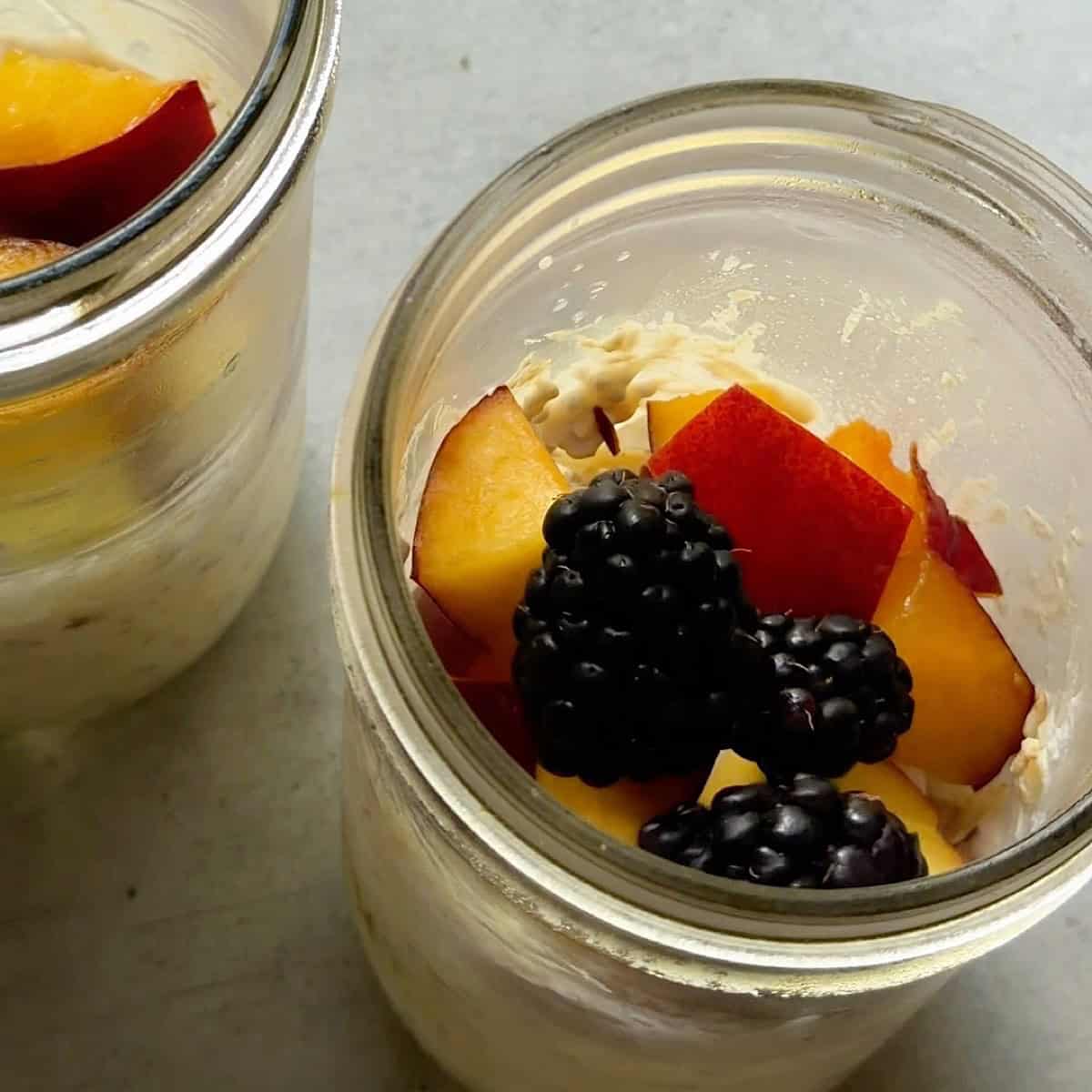 Almond, coconut, peach, and blackberry toppings added to the overnight oats.