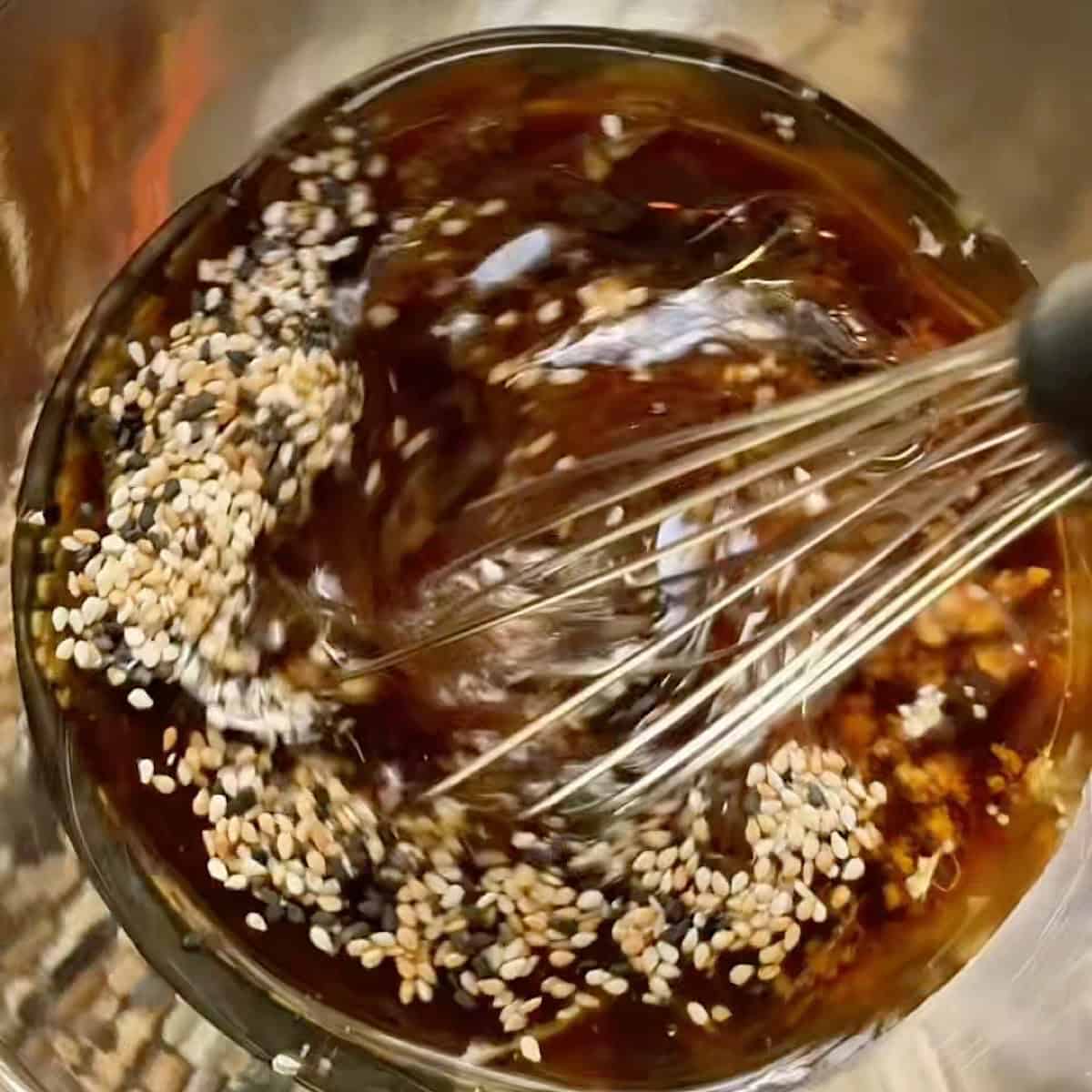 Whisking the ginger sesame dressing in a small bowl.