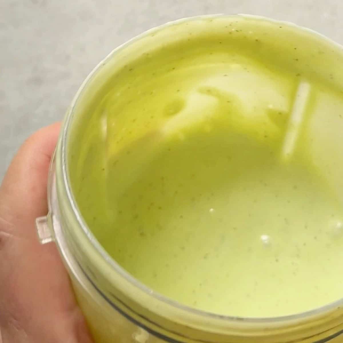 Holding blended avocado ranch dressing in a container.