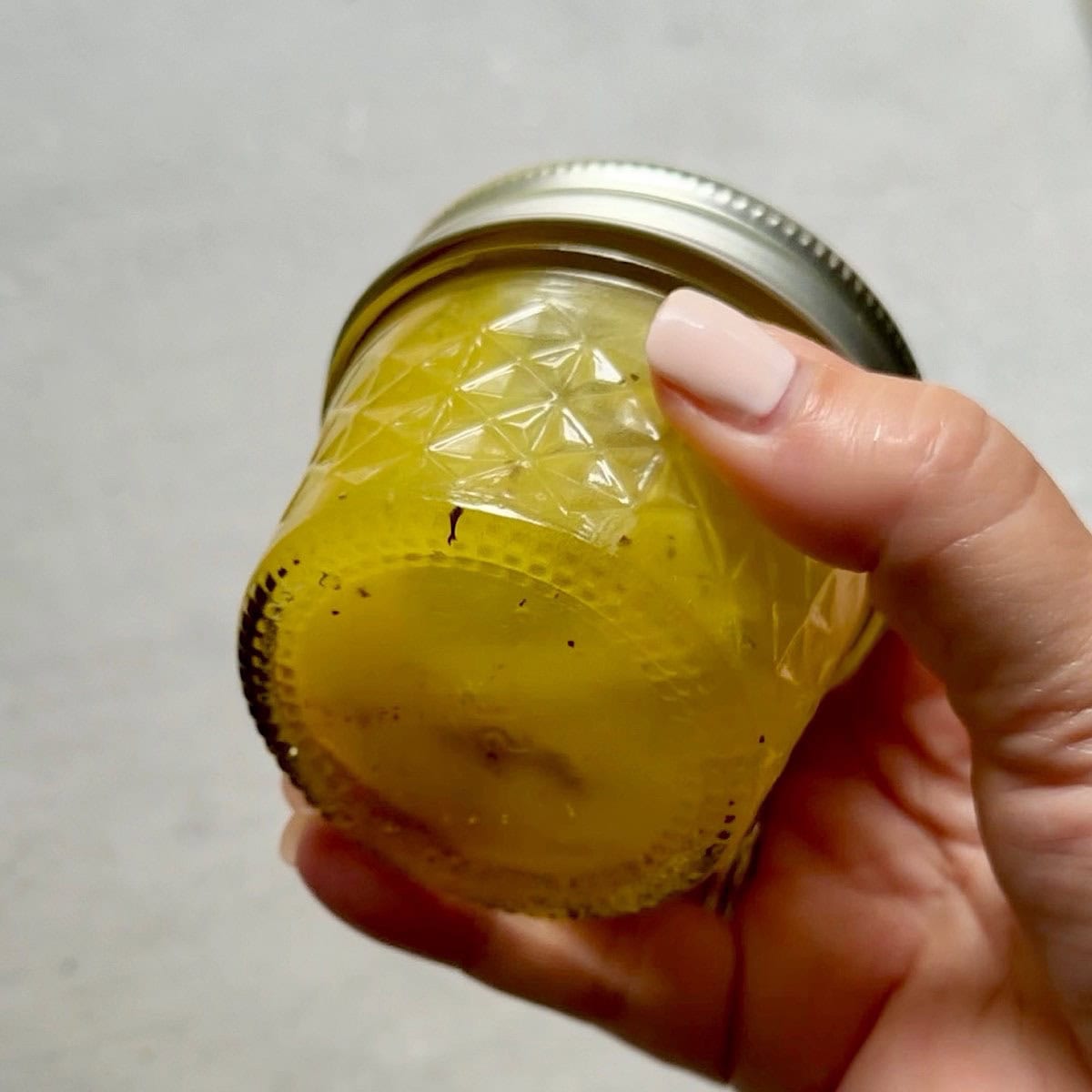 Shaking a jar of lemon vinaigrette.