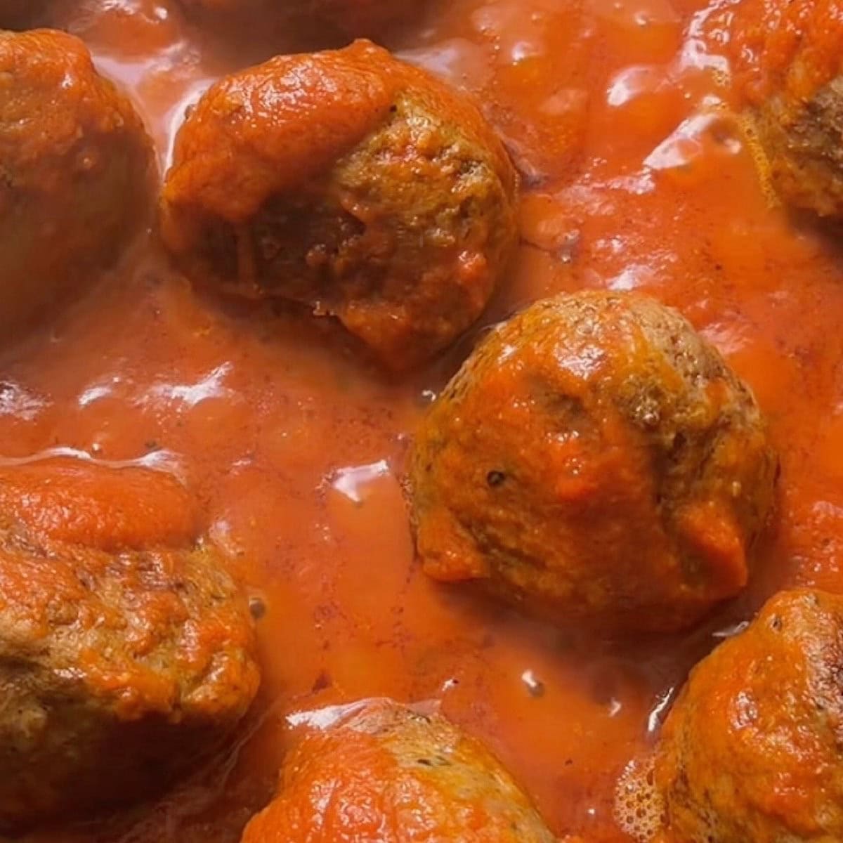 Meatballs simmering in marinara sauce.