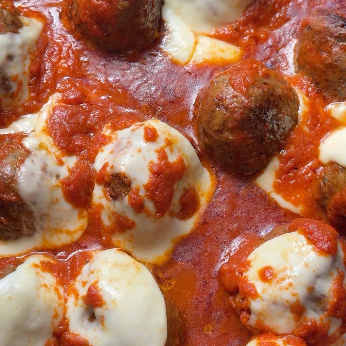 Baked meatballs in skillet with melted mozzarella on top.