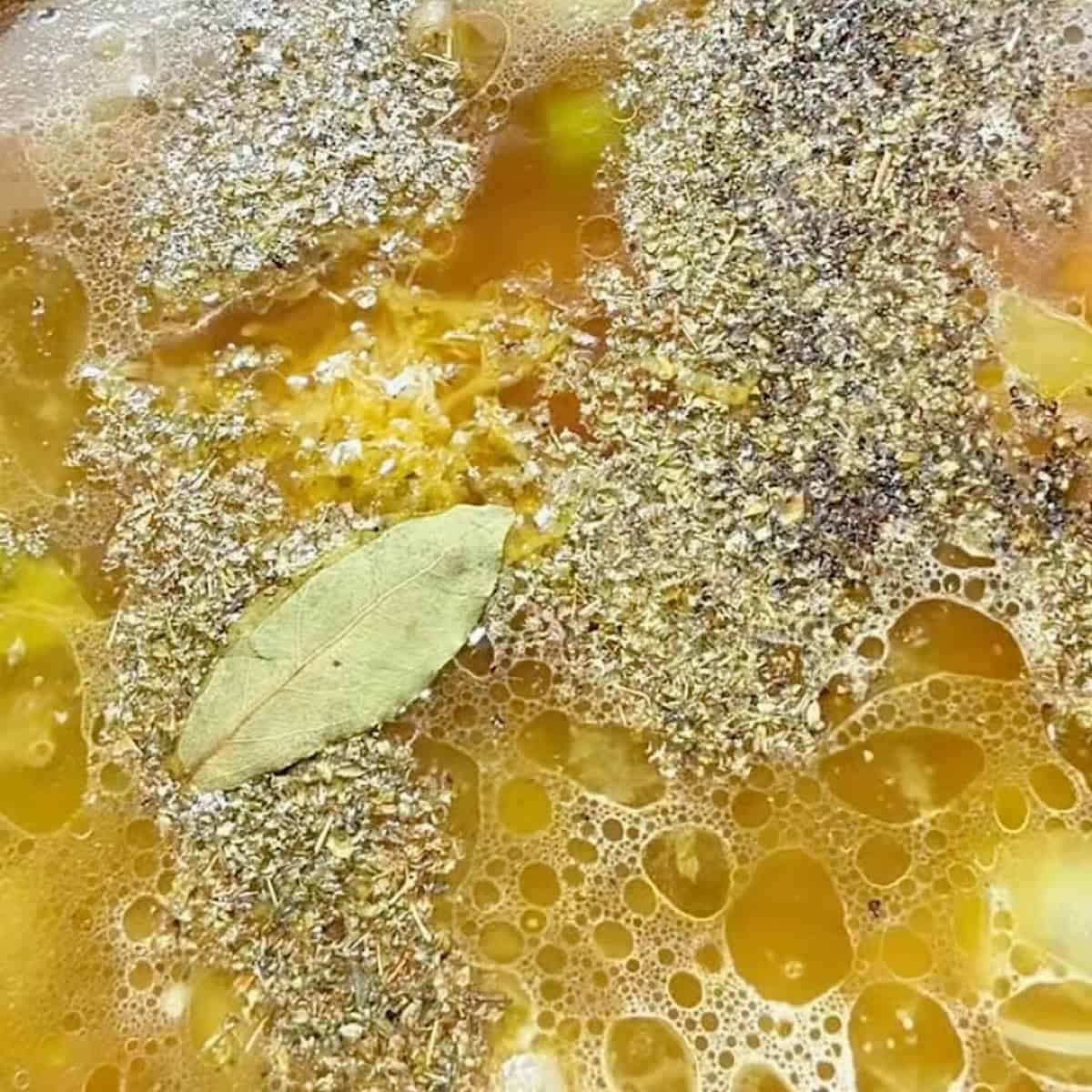 Preparing the Greek chickpea soup broth with seasonings.