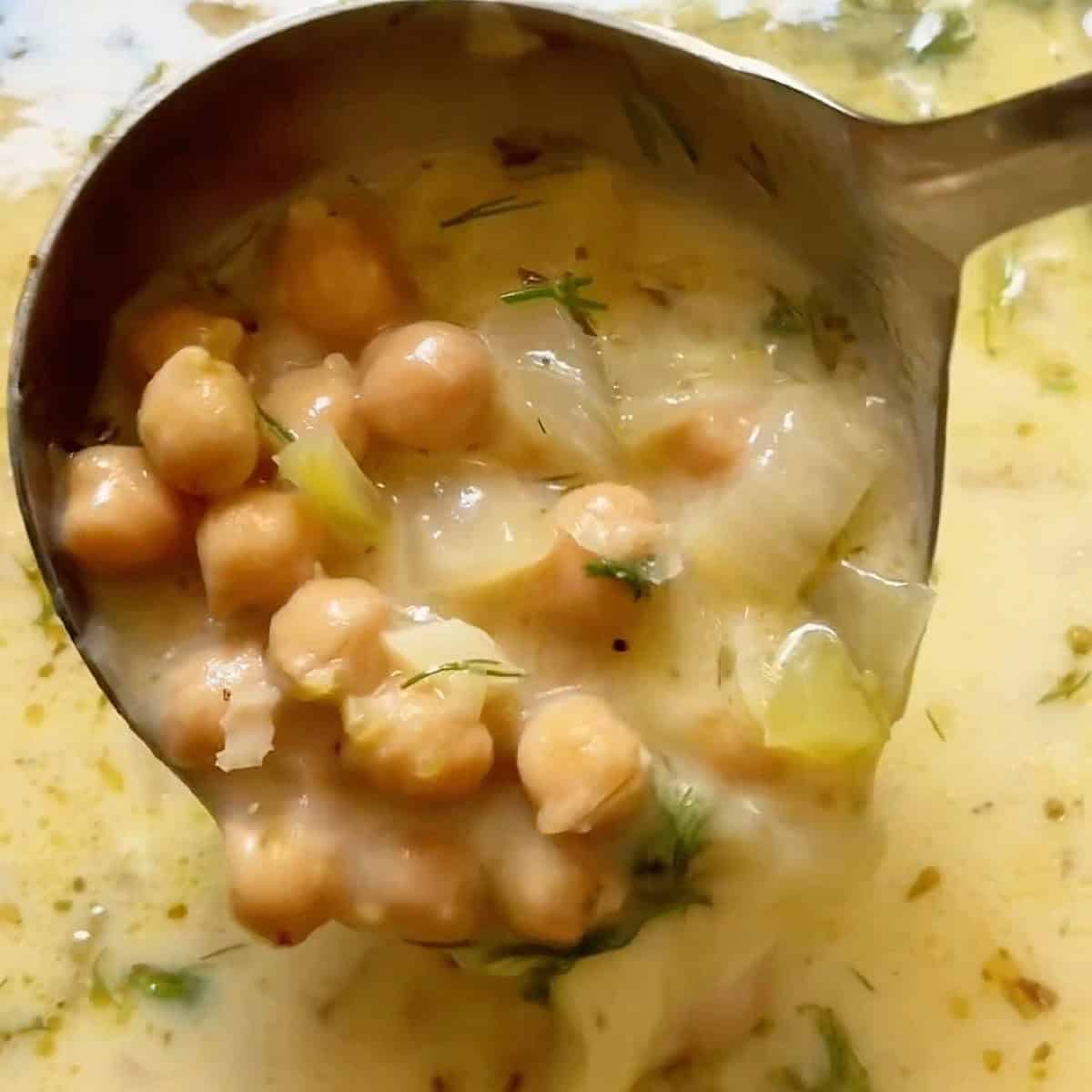 Holding a ladle full of Greek chickpea soup with the tempered egg and lemon.
