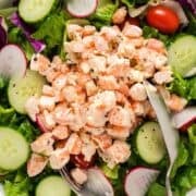 Old bay shrimp salad on a bed of greens and serving utensils.