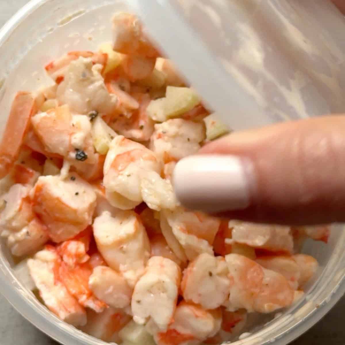 Removing the lid from the chilled container of old bay salad.