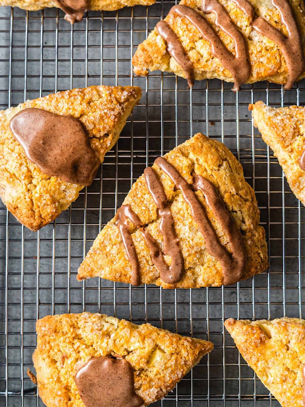 Apple cinnamon scones with maple glaze in different patterns on a wire rack.