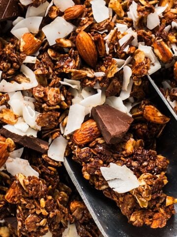 A scoop of dark chocolate coconut granola with visible coconut flakes and chocolate chunks.