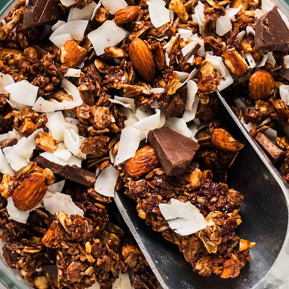 A scoop of dark chocolate coconut granola with visible coconut flakes and chocolate chunks.