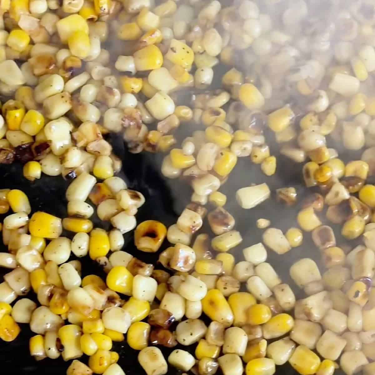 Charred corn smoking in a cast iron skillet.