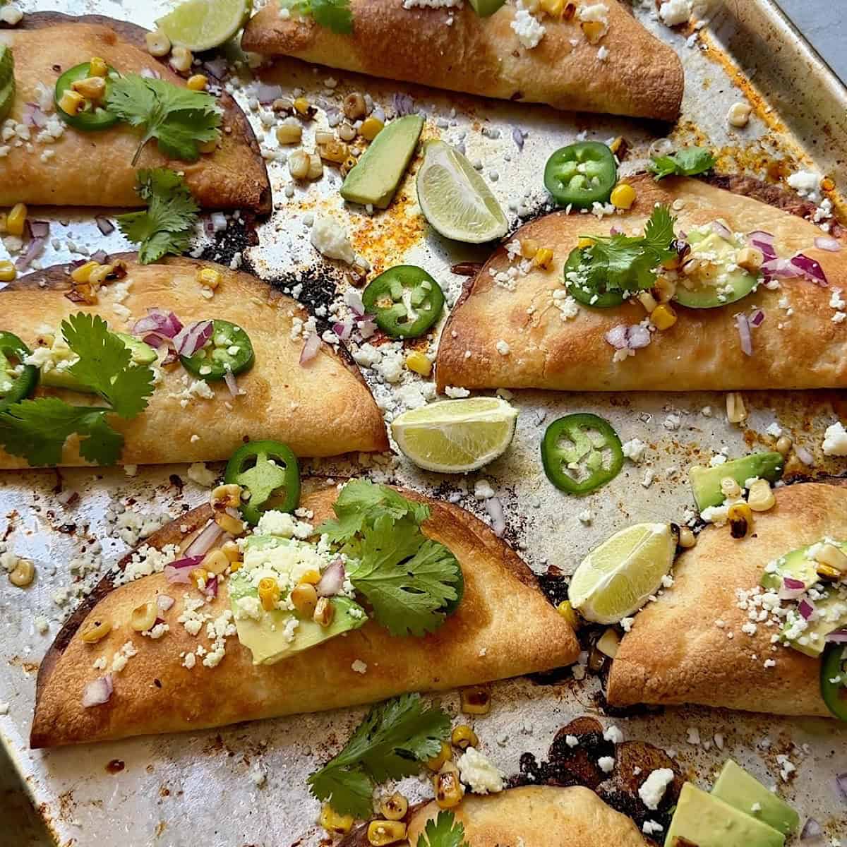 Fully prepared brisket tacos with avocado, jalapeno, lime, and cotija toppings.