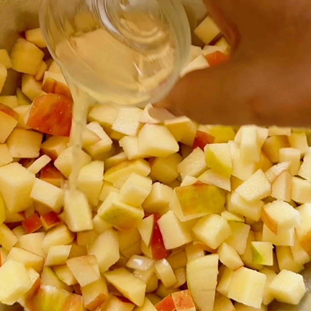 Pouring lemon juice over finely diced apples.