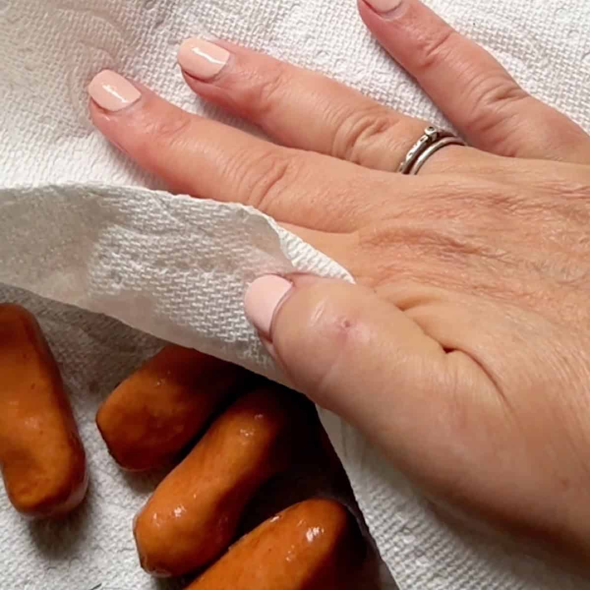 Drying the little smoky sausages with a paper towel.