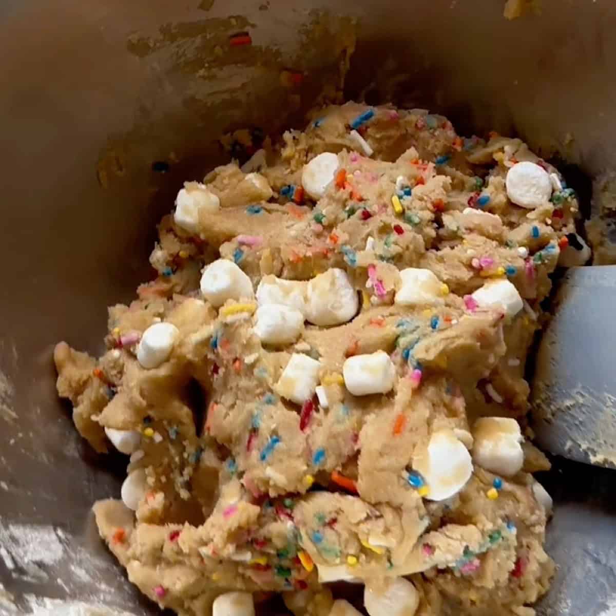 Wet and dry ingredients folded together with marshmallows and sprinkles.