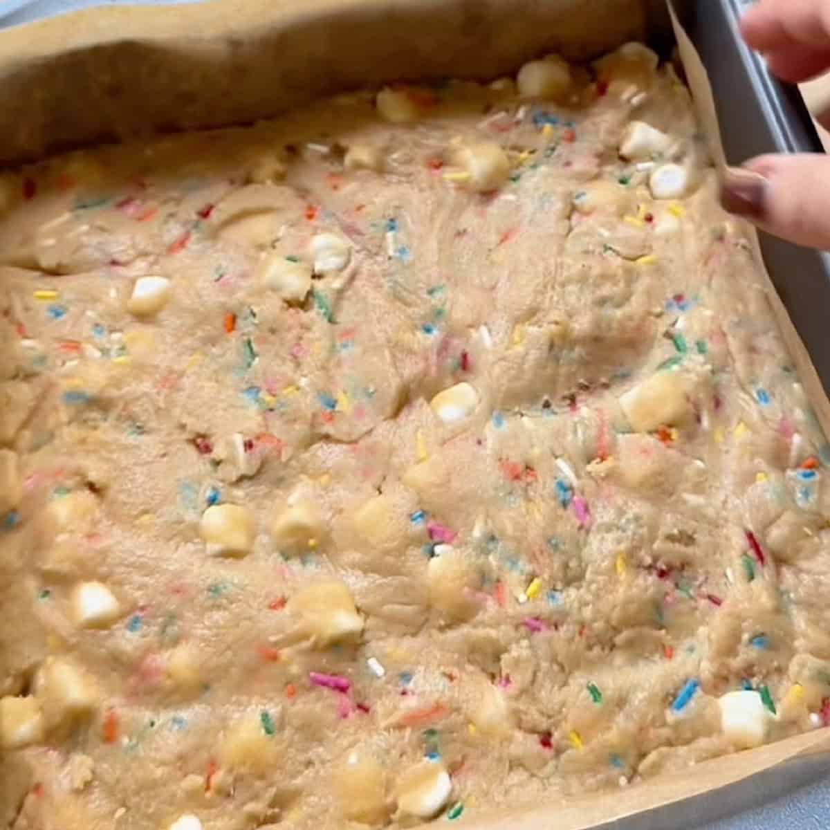 Funfetti batter spread evenly in a square baking dish.