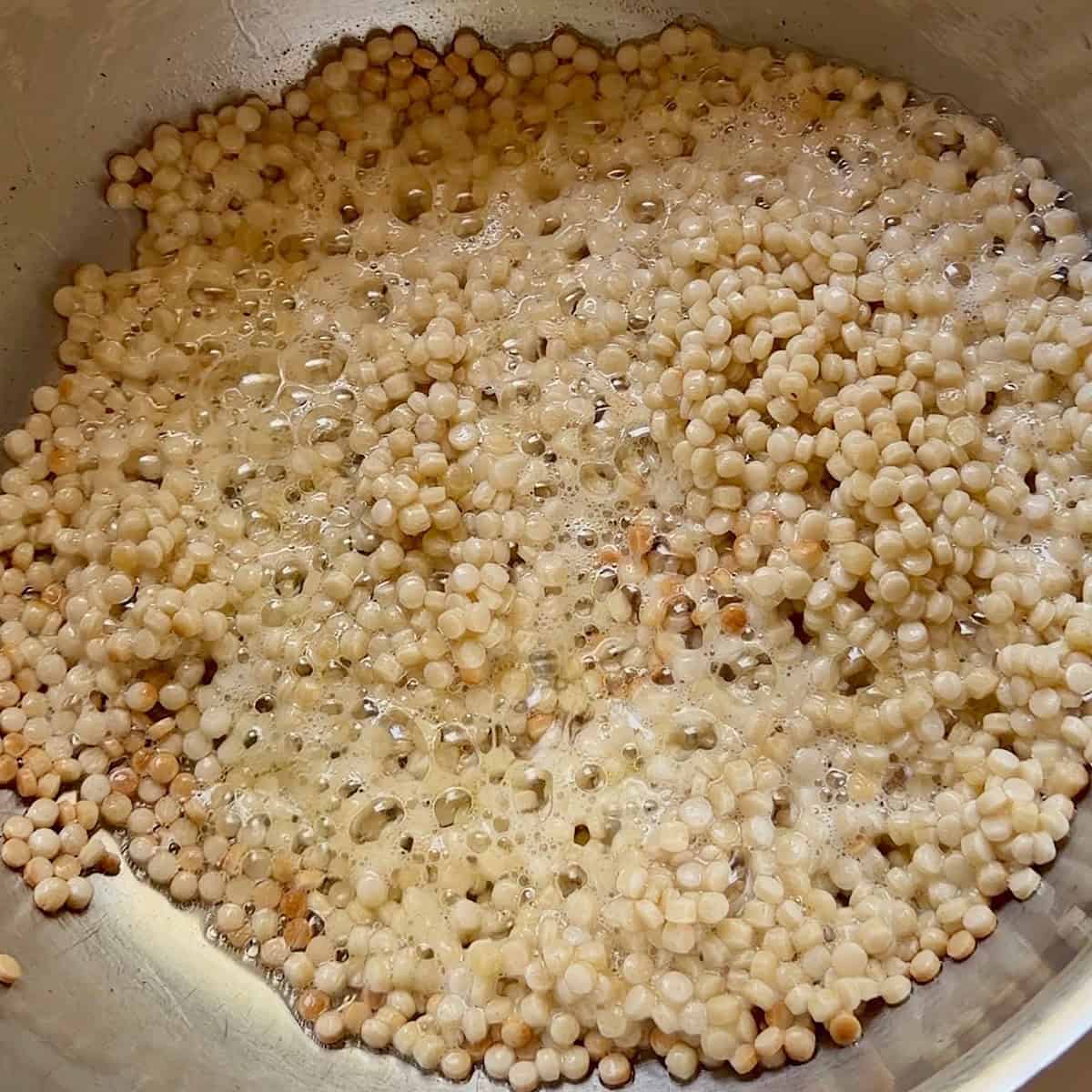 Toasted pearl couscous in oil and butter.