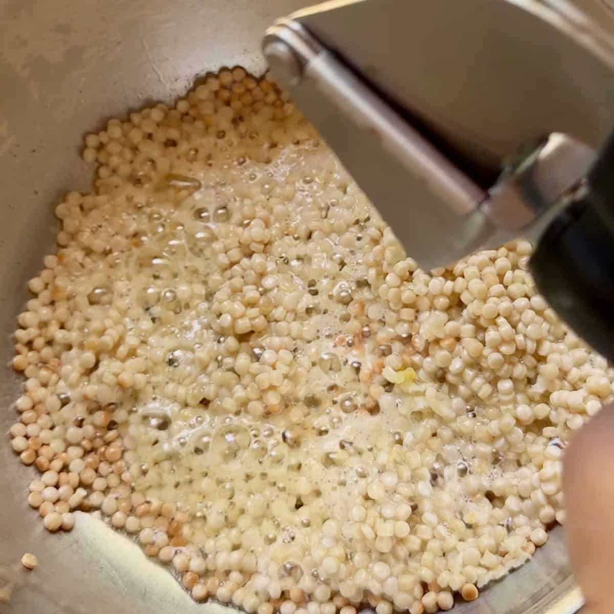 Using a garlic press to add the minced garlic.