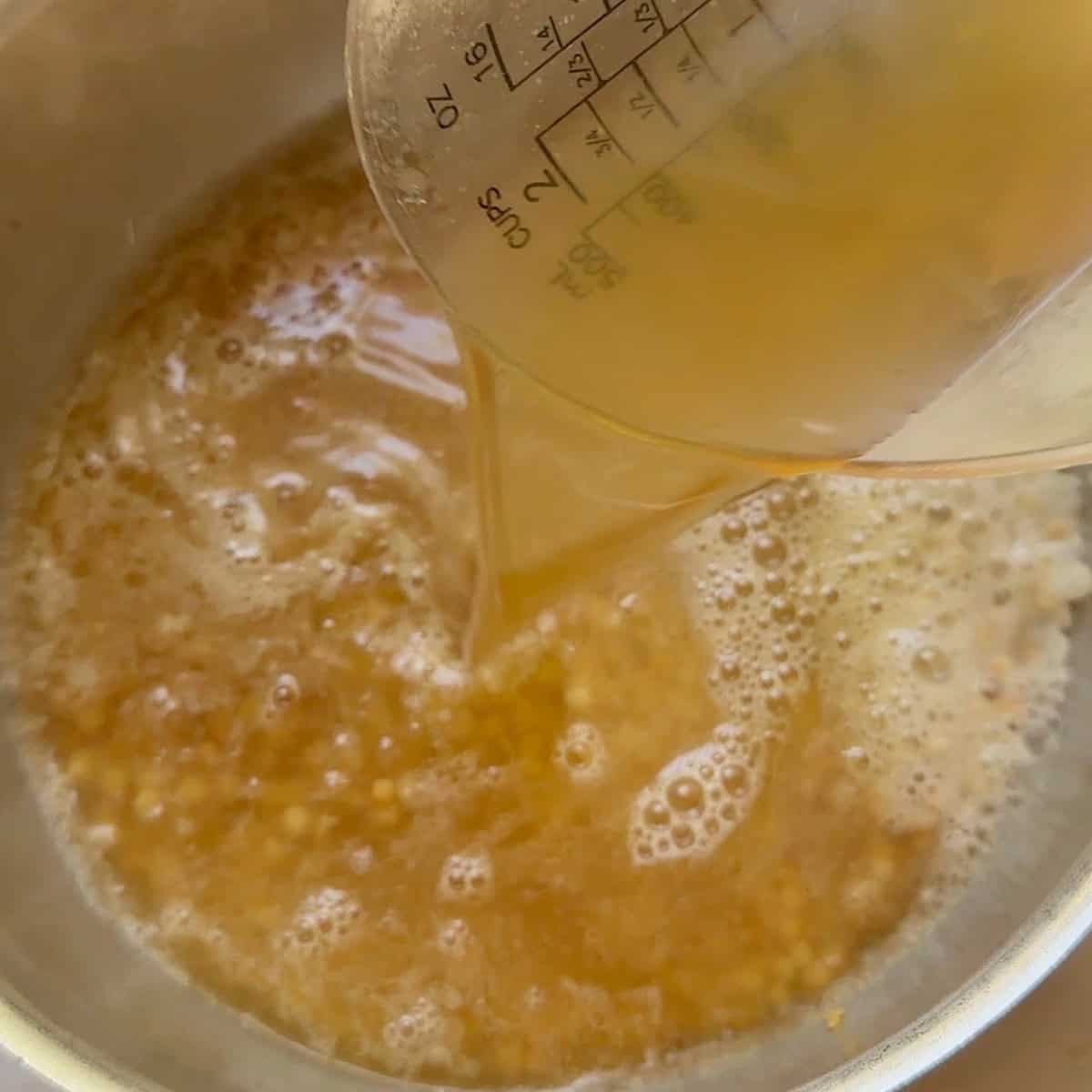 Pouring chicken broth into the pot.