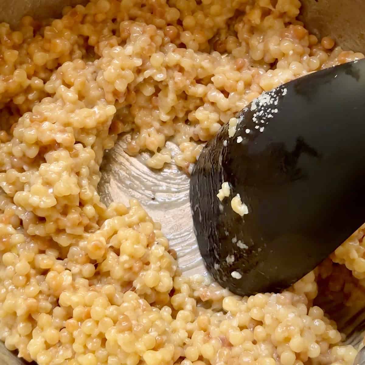 Stirring the Parmigiano-Reggiano into the finished couscous.