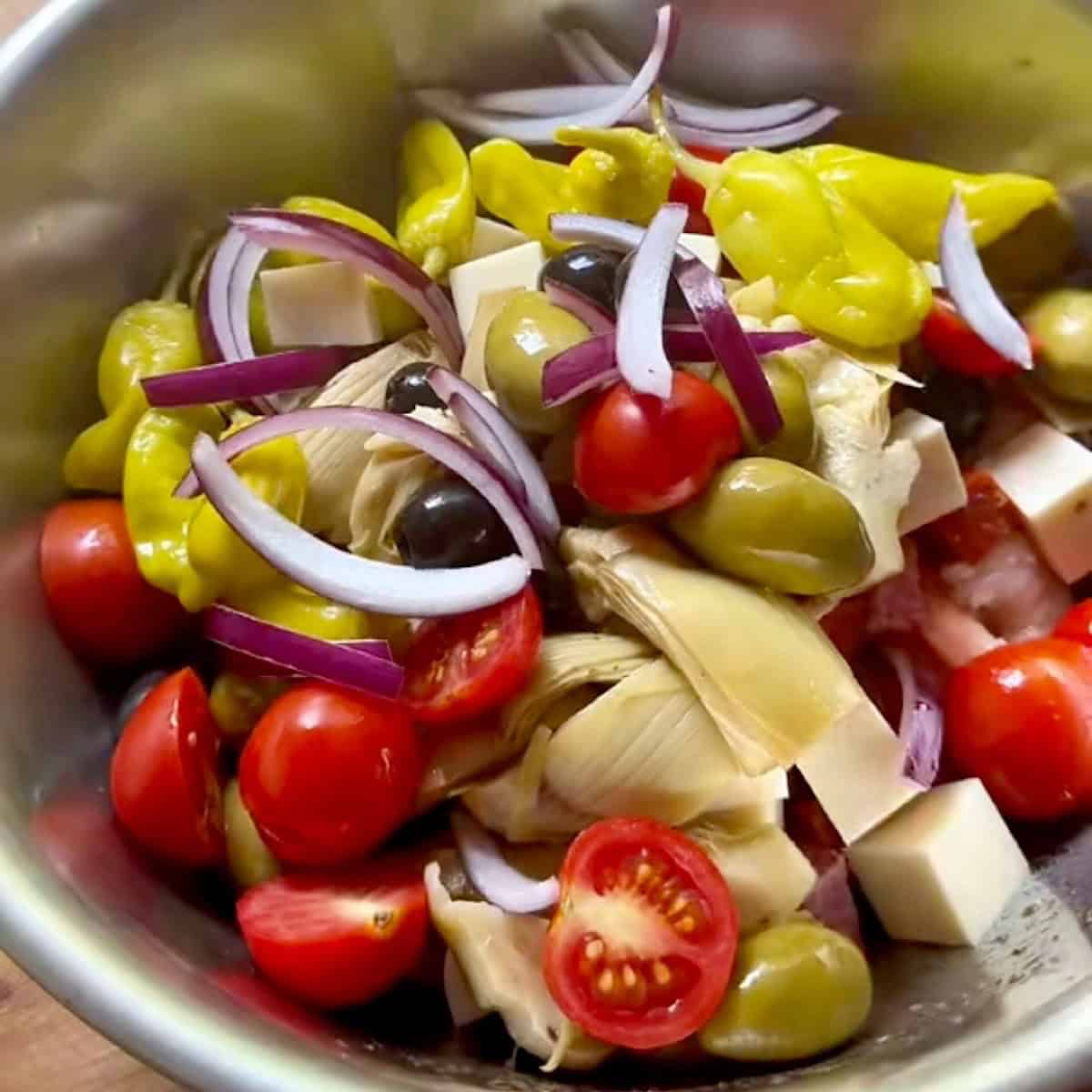 Shrimp antipasto salad ingredients in a mixing bowl.