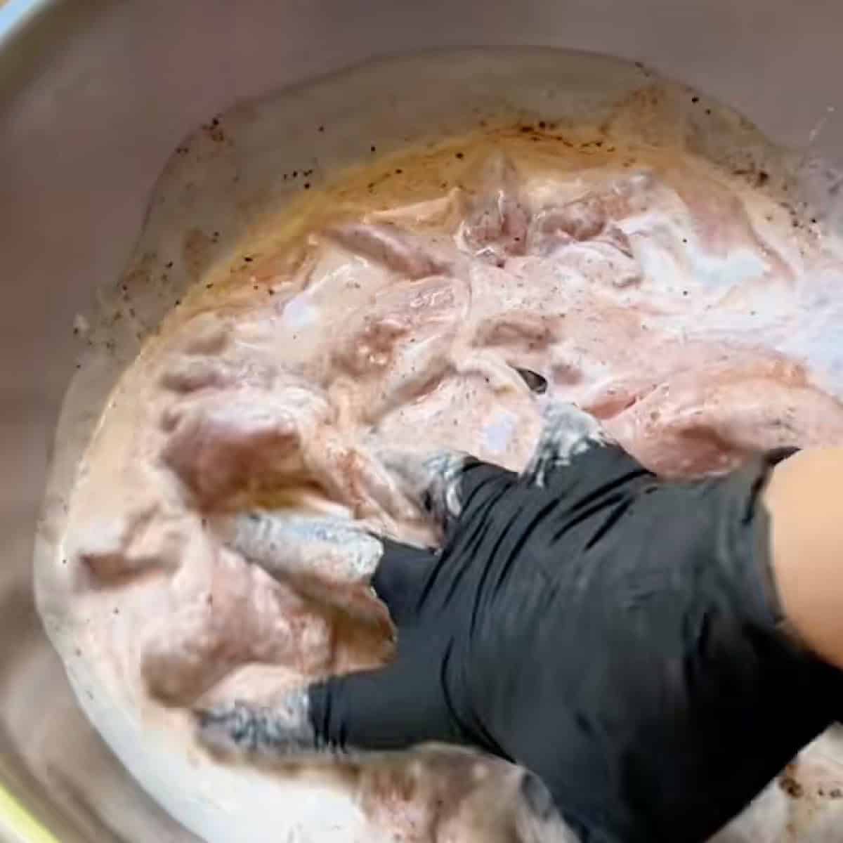 Boneless chicken thighs submerged in buttermilk marinade.