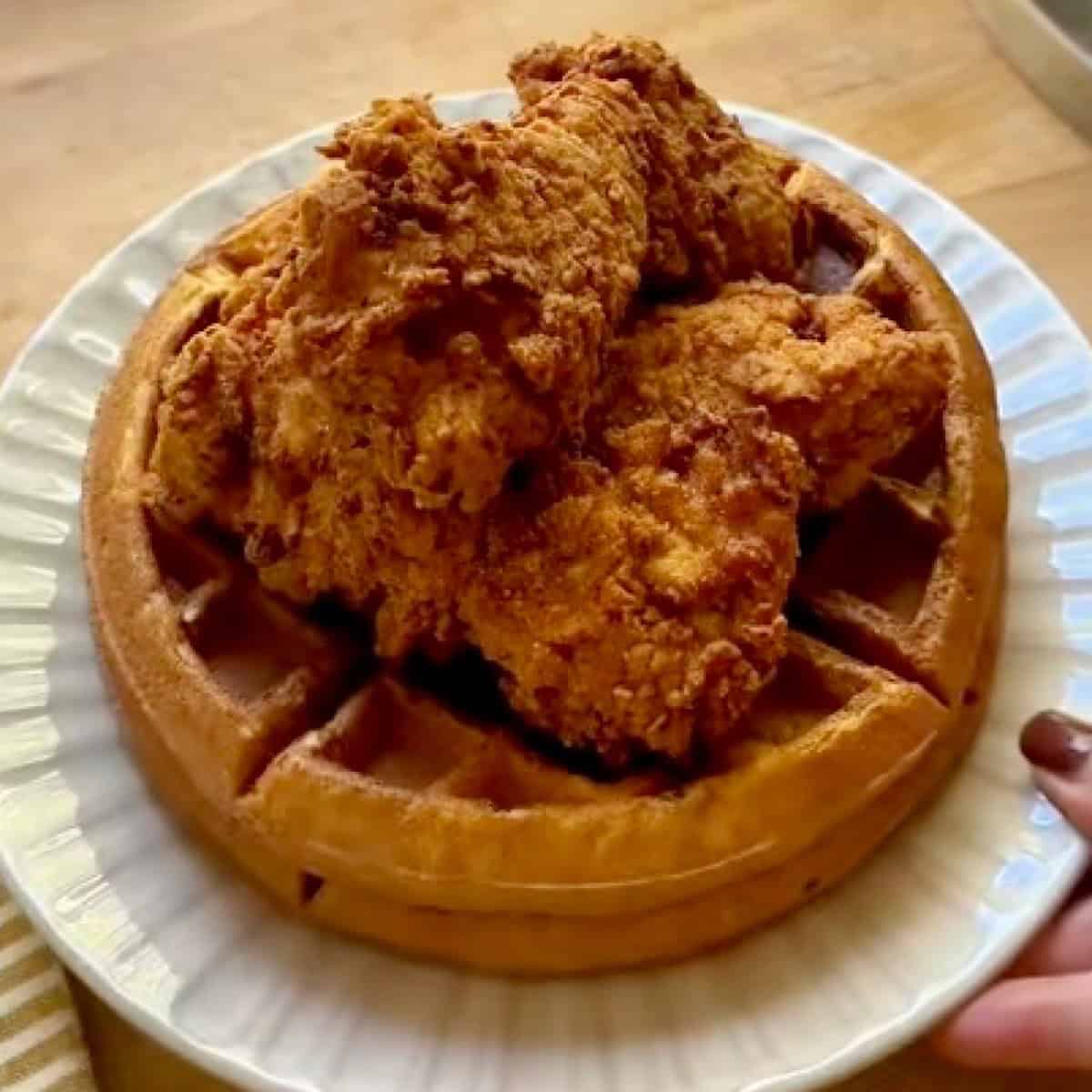 A double stack of Belgian waffles with fried chicken resting on top.