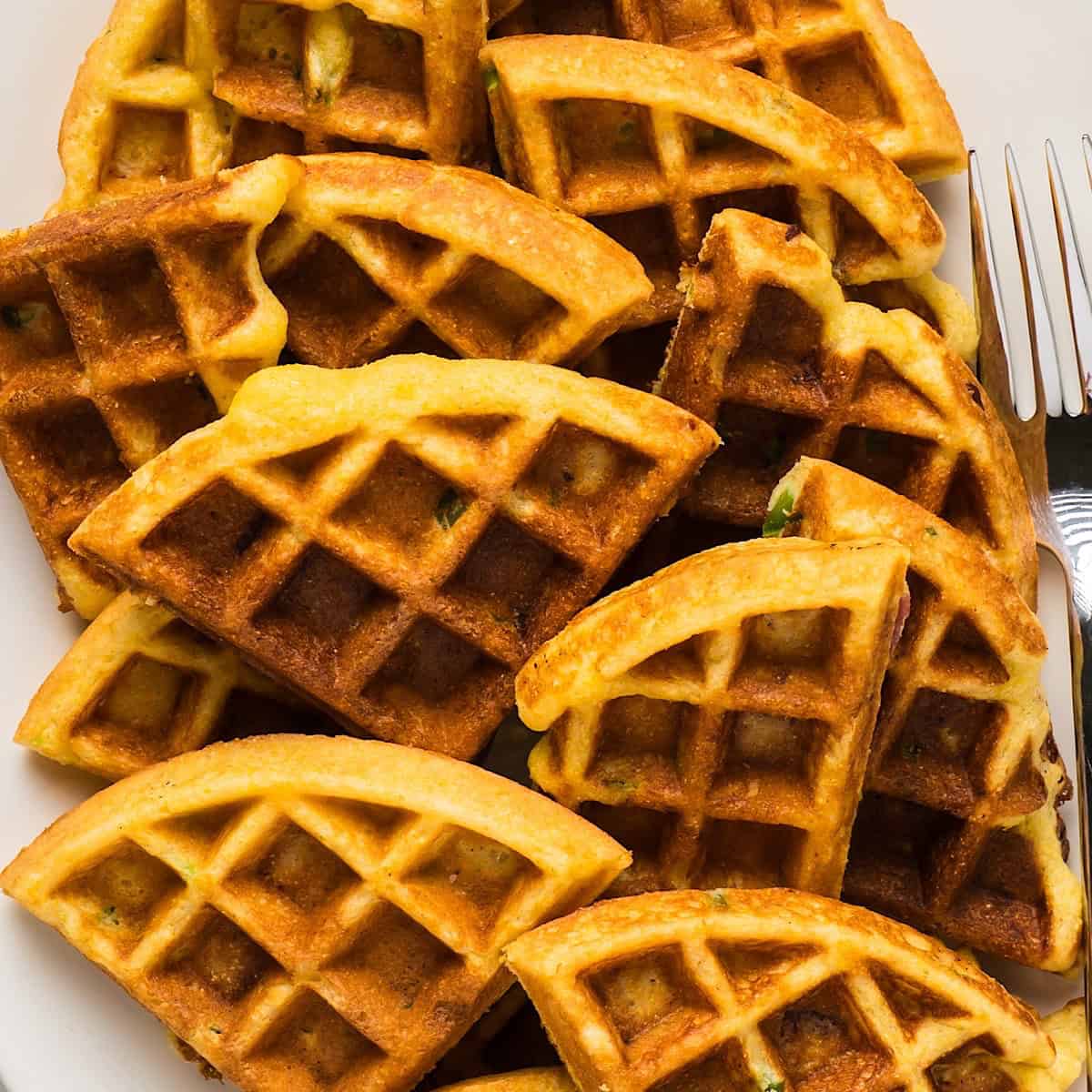 Bacon Jalapeno Cornbread Waffles wedges on a platter with a silver fork.