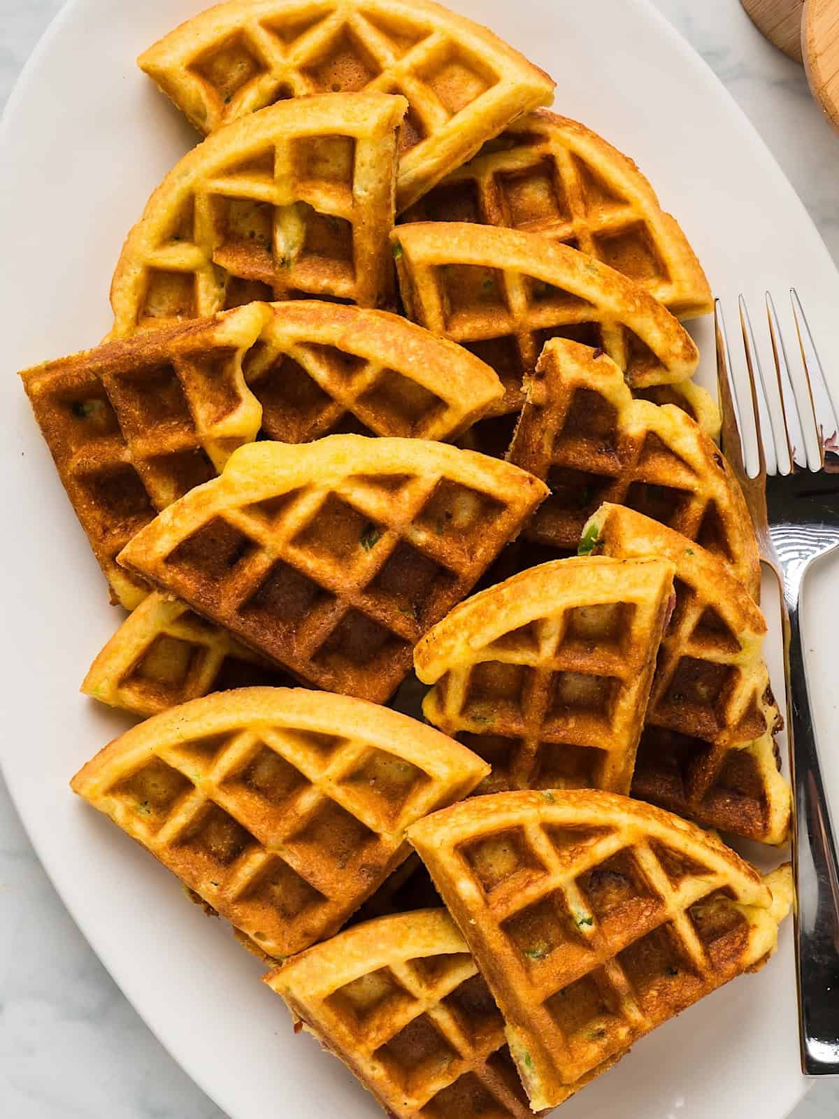 Bacon Jalapeno Cornbread Waffles wedges on a platter with a silver fork.