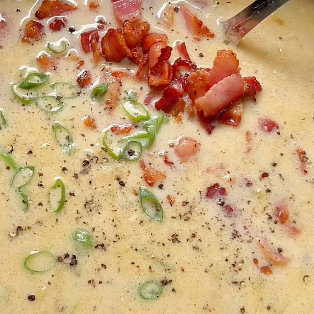 Thickened bacon potato leek soup with blended ingredients and garnish.