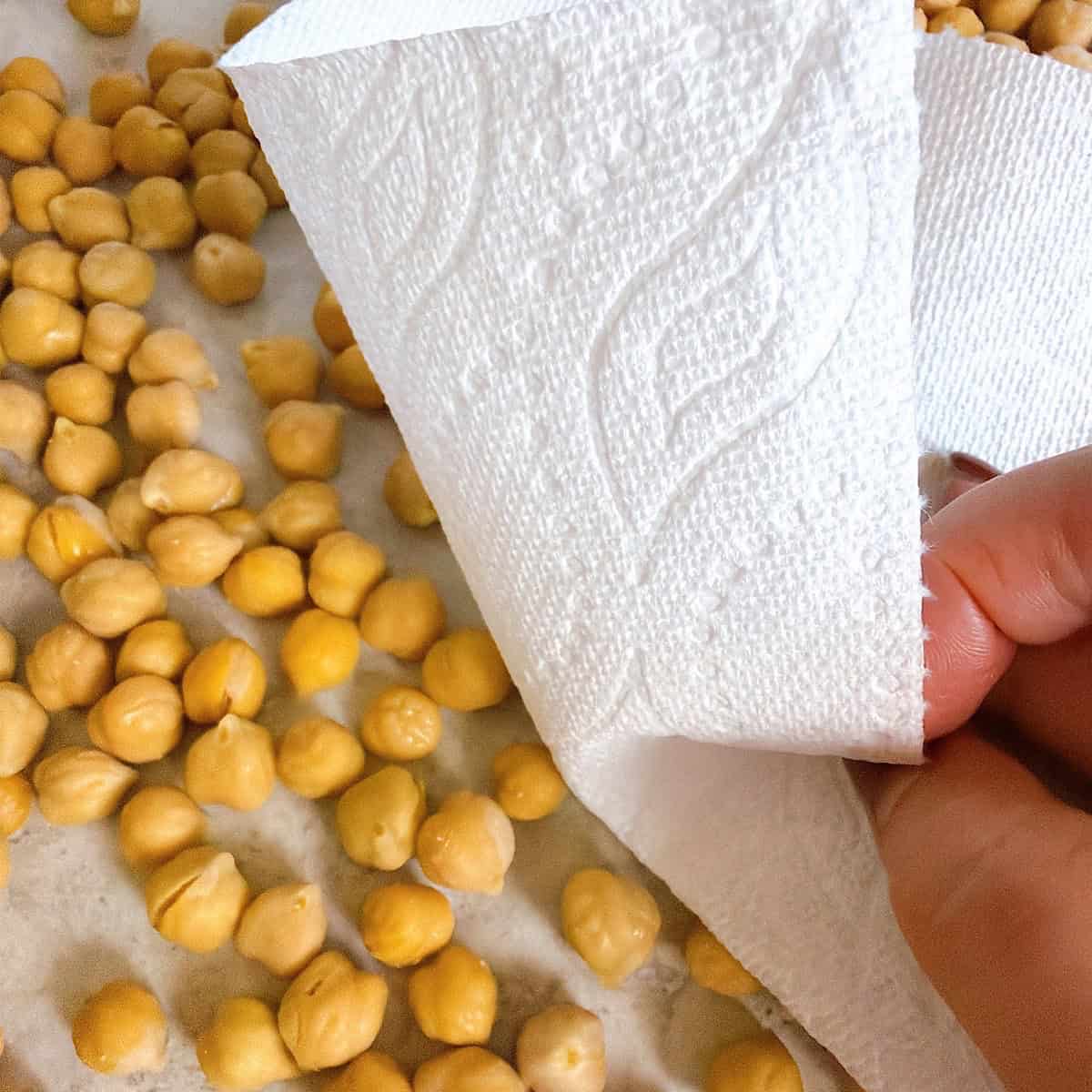 Drying the garbanzo beans with a paper towel.