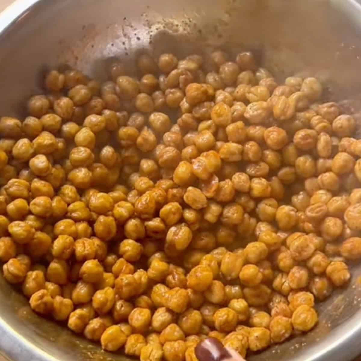 Tossing the roasted chickpeas in buffalo sauce.