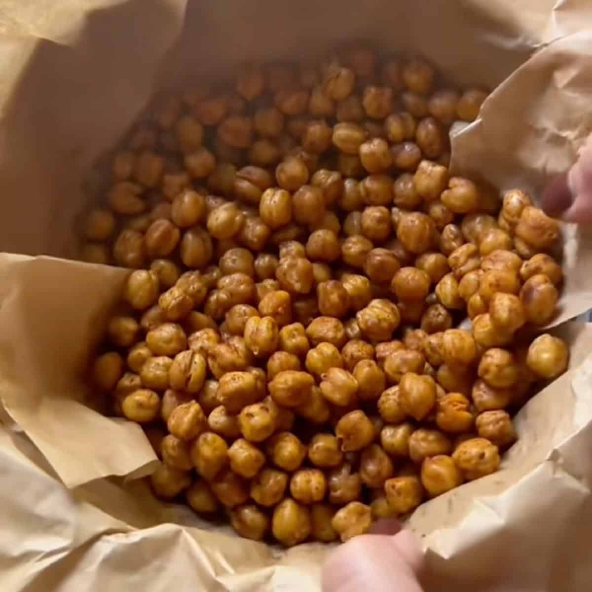 Cooled chickpeas in a parchment lined bowl dusted with seasoning.