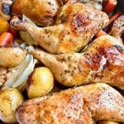 Herb roasted chicken with carrots and potatoes nestled into a roasting pan.