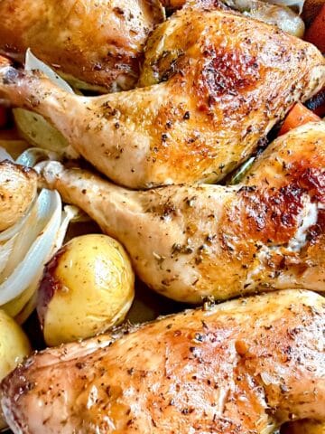 Herb roasted chicken with carrots and potatoes nestled into a roasting pan.