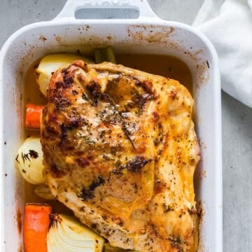 Herb roasted turkey breast in casserole dish next to linen.