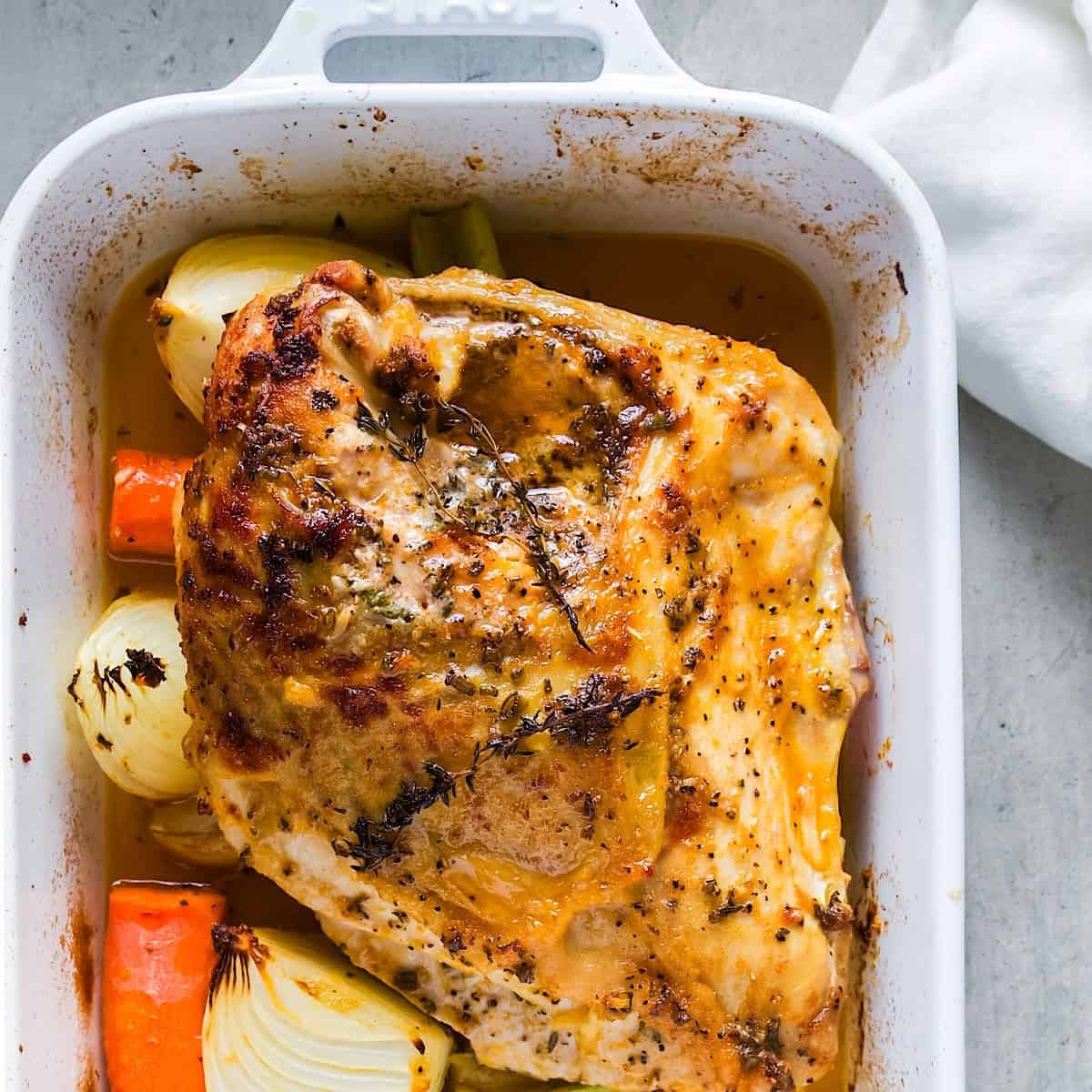 Herb roasted turkey breast in casserole dish next to linen.